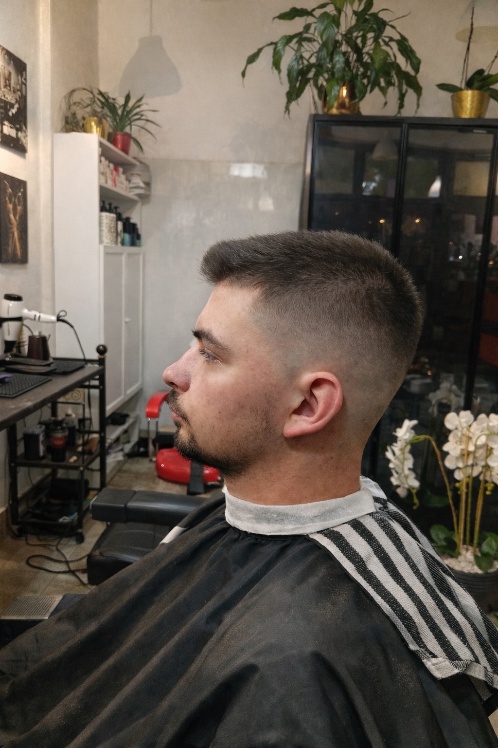 Mężczyzna po strzyżeniu z krótkim fade po bokach i dłuższą górą siedzi w salonie barberskim po zakończonej stylizacji