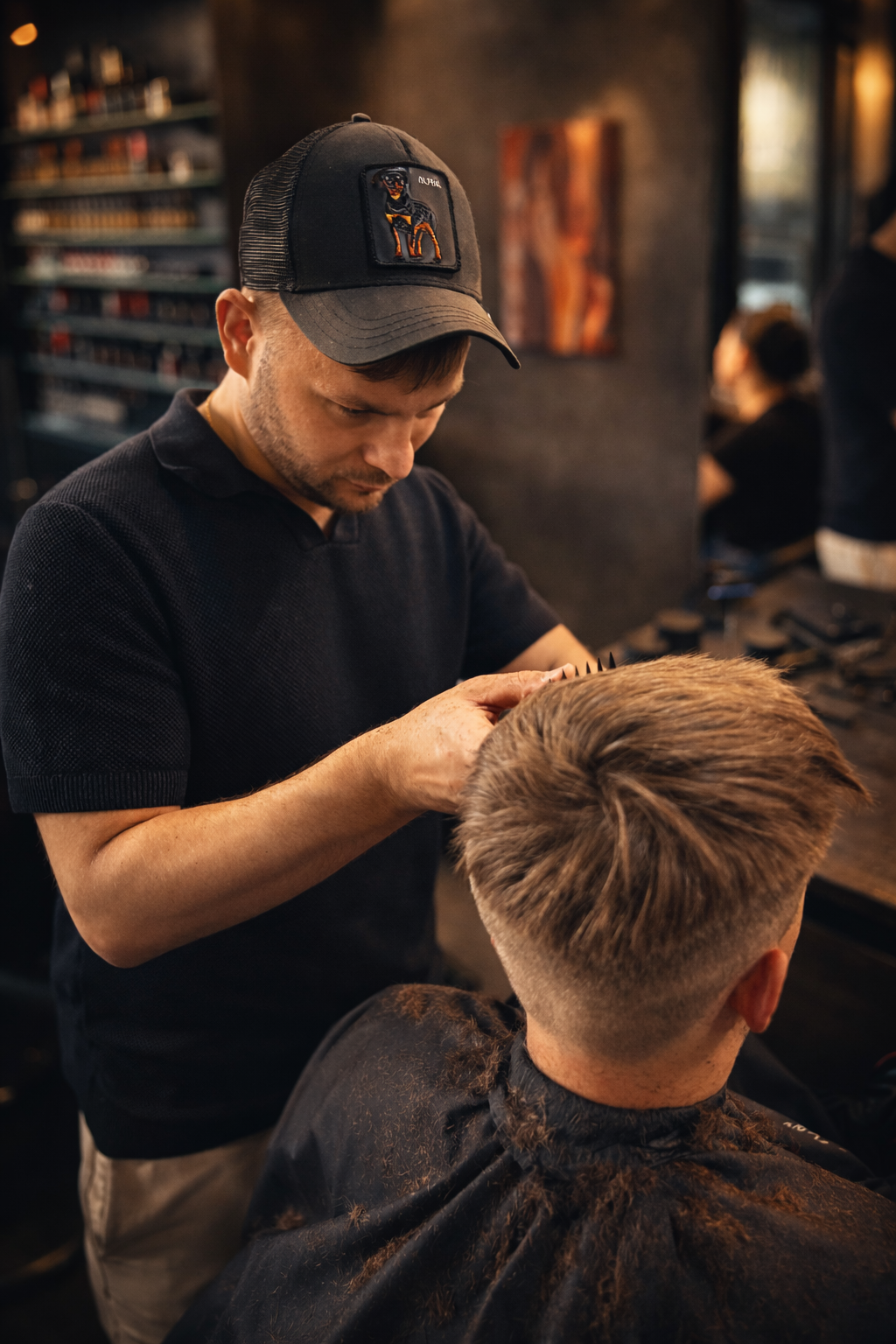 Barber modeluje włosy klienta, dopracowując fryzurę po strzyżeniu w profesjonalnym i klimatycznym salonie barberskim