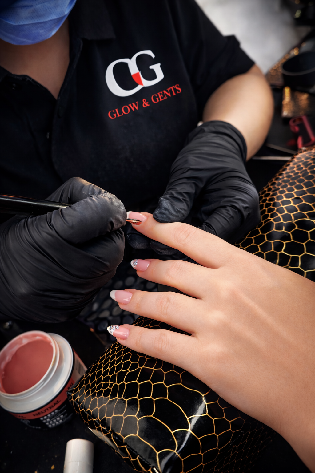 Stylistka nakłada żel na paznokcie klientki, precyzyjnie modelując manicure w profesjonalnym salonie kosmetycznym