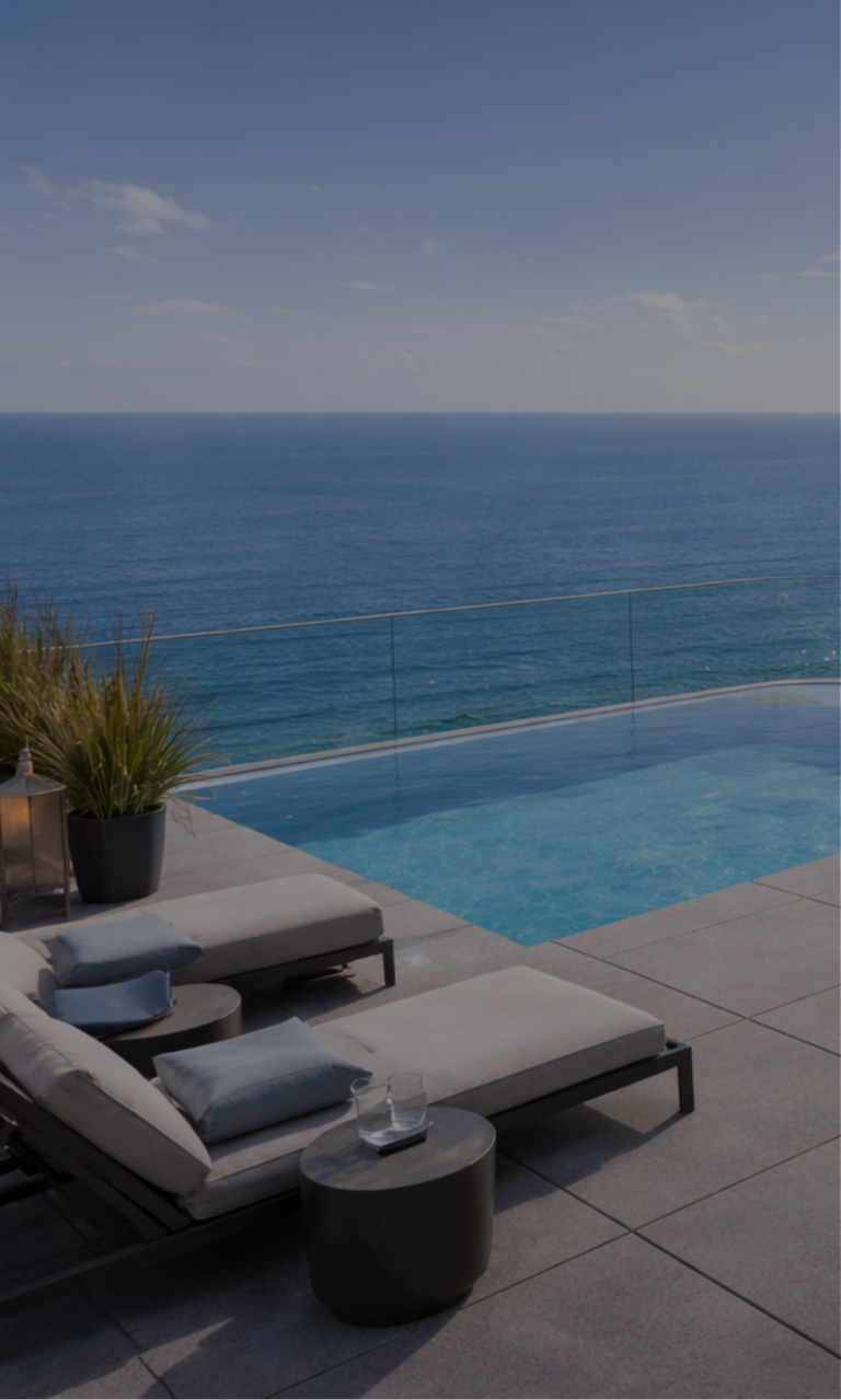 Nowoczesny taras przy basenie z leżakami i widokiem na morze oraz horyzont.