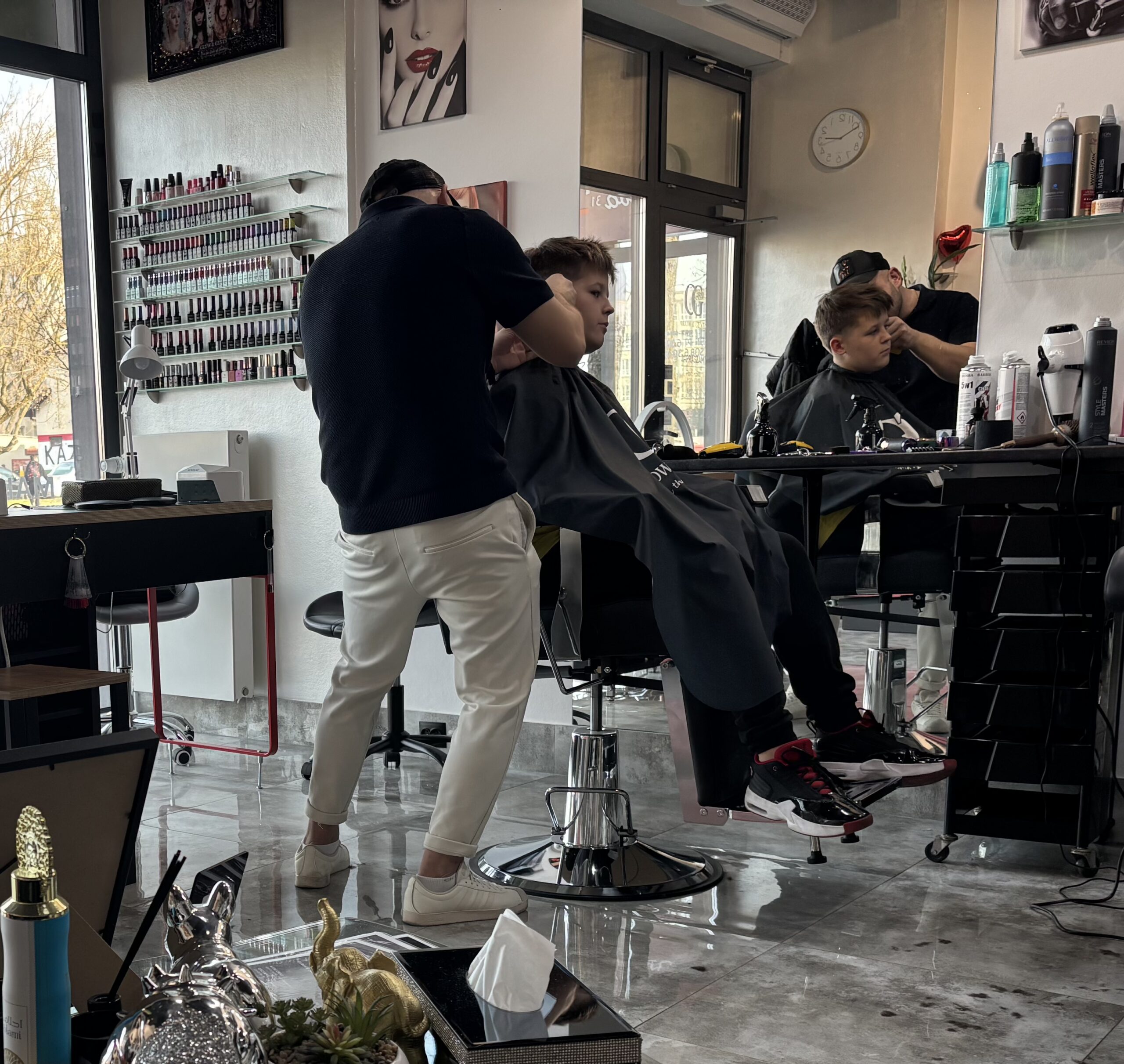 Barber strzyże włosy chłopca na fotelu fryzjerskim, wykonując precyzyjne cięcie w nowoczesnym salonie fryzjerskim