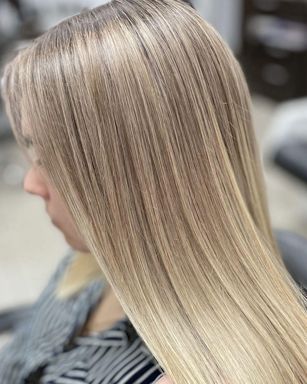 Proste, lśniące włosy blond o równomiernym kolorze i gładkiej strukturze po profesjonalnej stylizacji w salonie