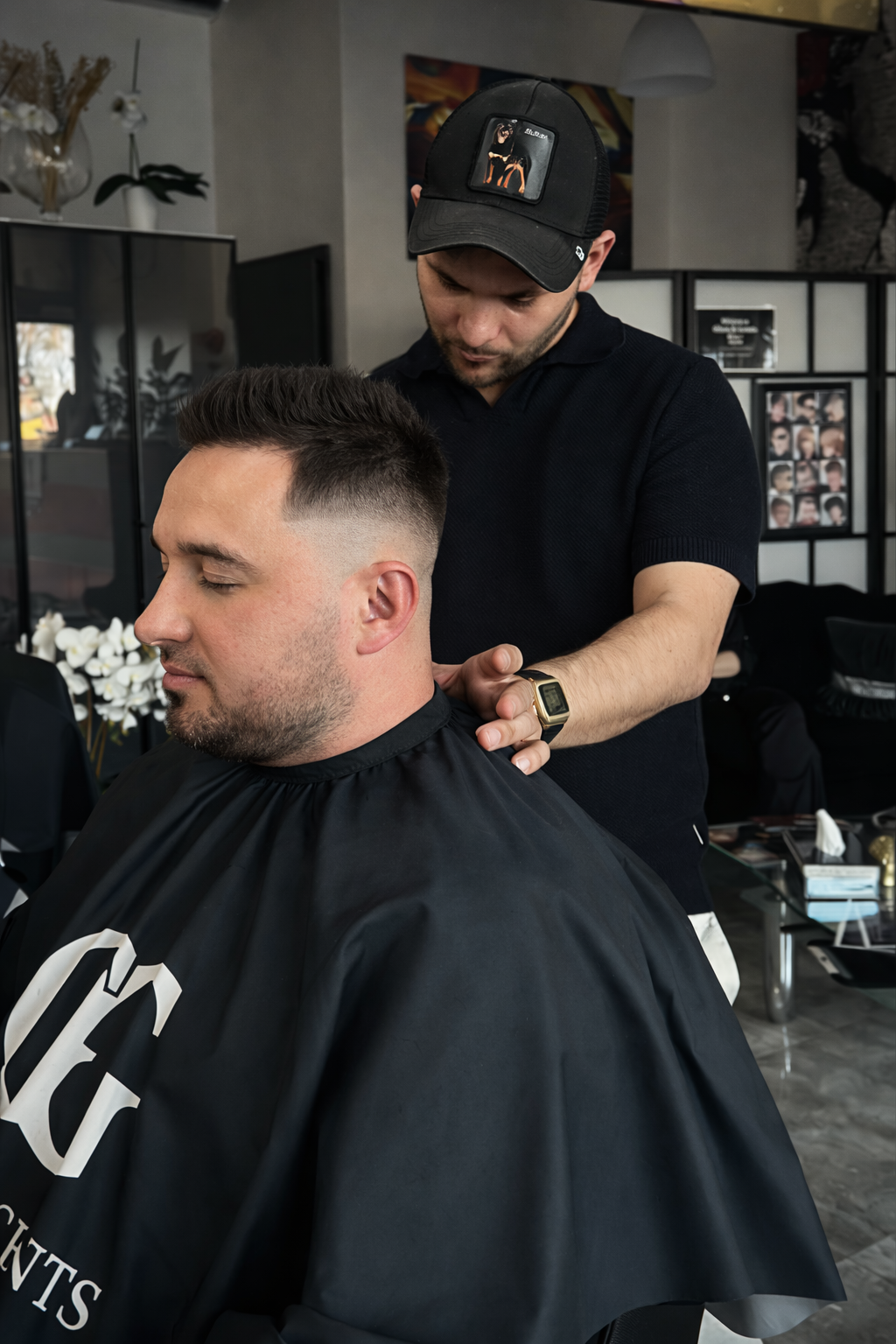 Barber dopracowuje fryzurę mężczyzny z wyraźnym fade po bokach, wykonując końcową stylizację w salonie barberskim