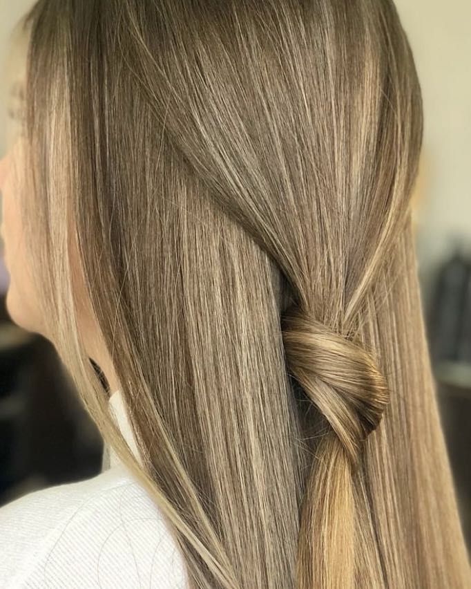 Długie, proste włosy w odcieniach blond z delikatnym upięciem z tyłu, tworzące elegancką i naturalną fryzurę