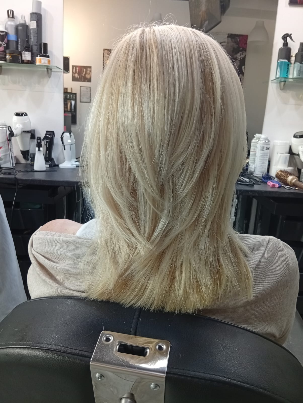 Jasny platynowy blond z warstwowym cięciem i lekkim wywinięciem końcówek po stylizacji fryzjerskiej.