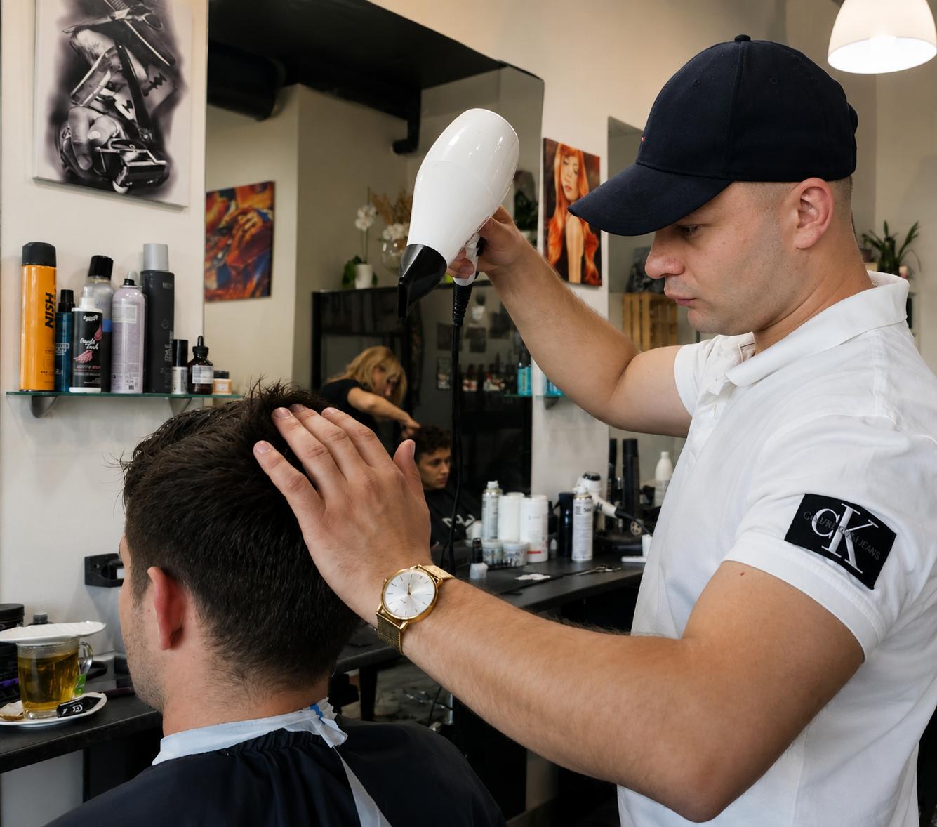 Fryzjer modelujący męską fryzurę suszarką podczas końcowej stylizacji w salonie fryzjerskim.