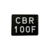 Czarna tablica rejestracyjna do motocykla z białym oznaczeniem „CBR 100F”.