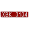 Czerwona tablica rejestracyjna z białym napisem „XBK 0104”.